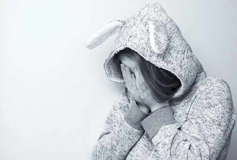 A child hiding their face in distress — the impact of religious conflict on children in families